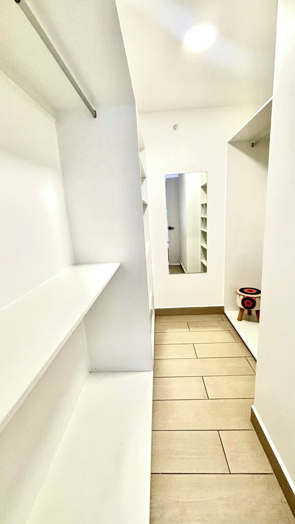 A narrow hallway with white walls, a tiled floor, and a small stool in the corner. - Living 73 Panamá by Boutique Apartments (Panama City)