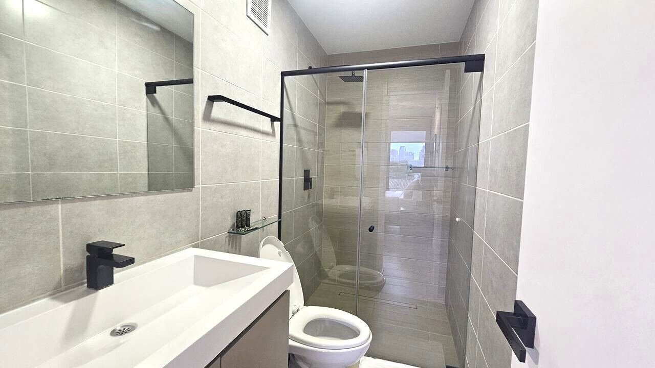A modern bathroom with a glass shower enclosure, a white sink, and a toilet.