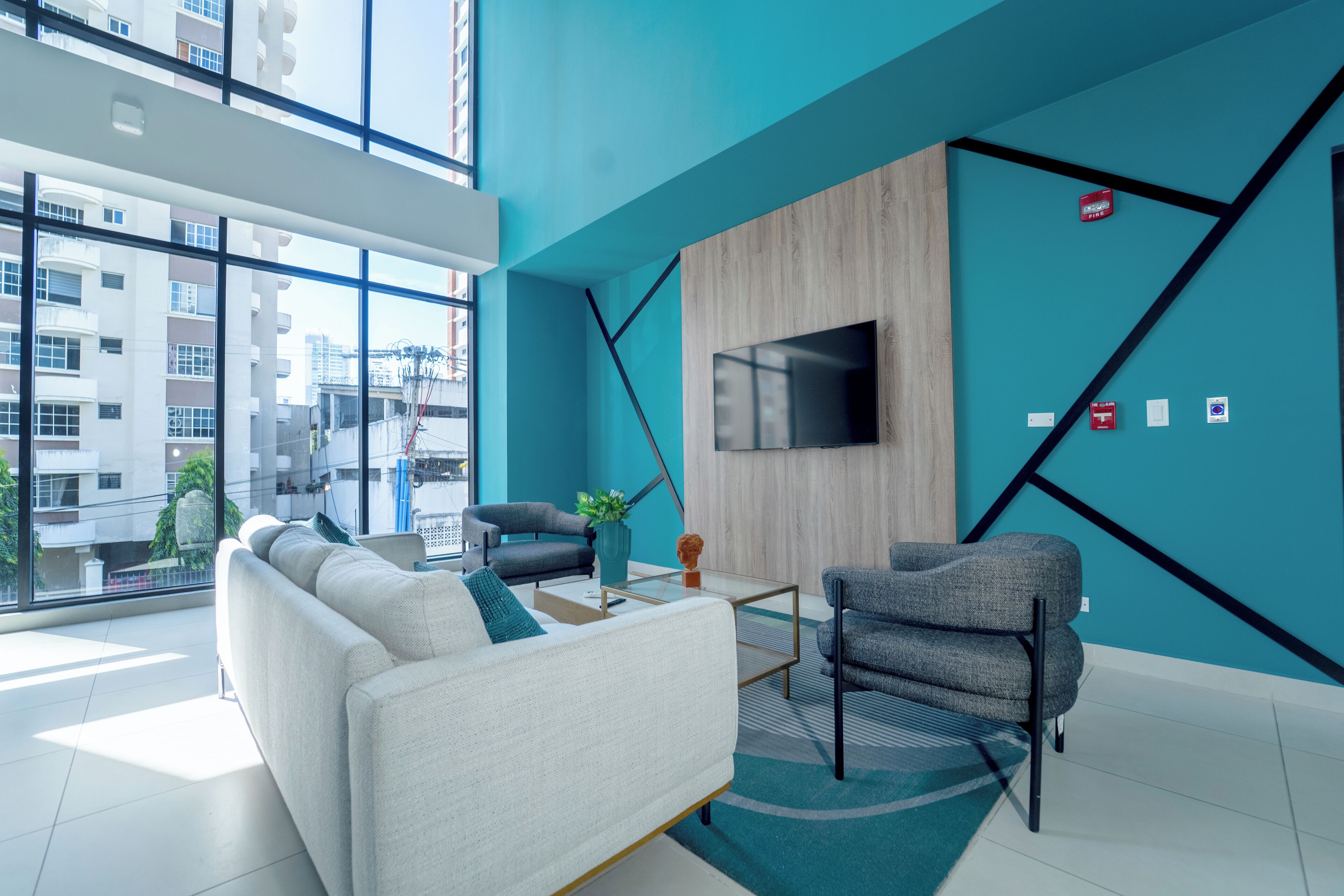 Uma sala de estar moderna com sofá, poltronas, mesa de centro e televisão na parede.