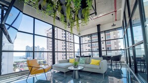 A modern interior with a glass floor, a sectional sofa, yellow cushions, and hanging plants. - Living 73 Panamá by Boutique Apartments (Panama City)