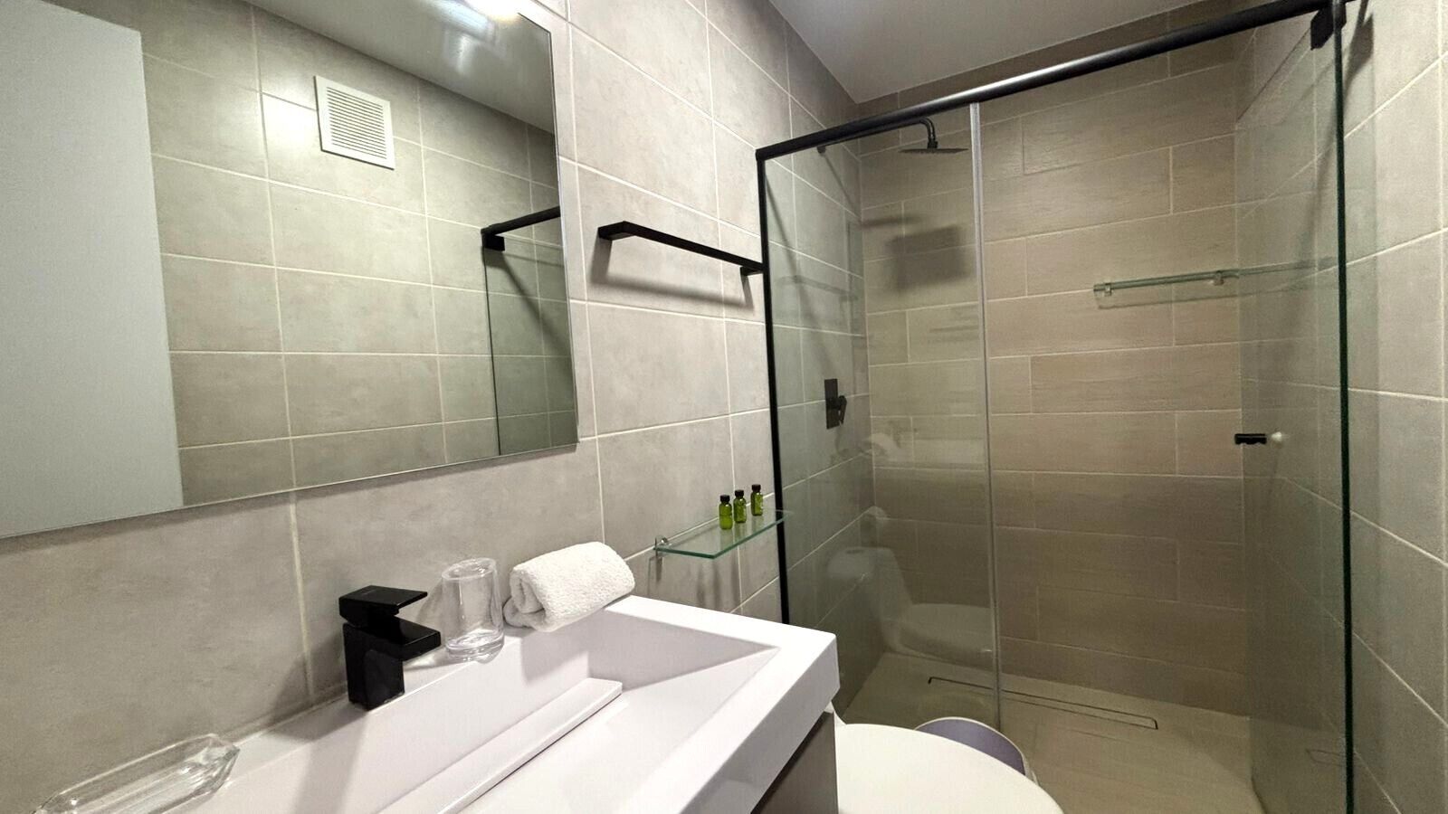 Une salle de bain moderne avec une douche à parois de verre, un lavabo blanc et un miroir.