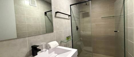 Un baño moderno con cabina de ducha de vidrio, un lavabo blanco y un espejo.