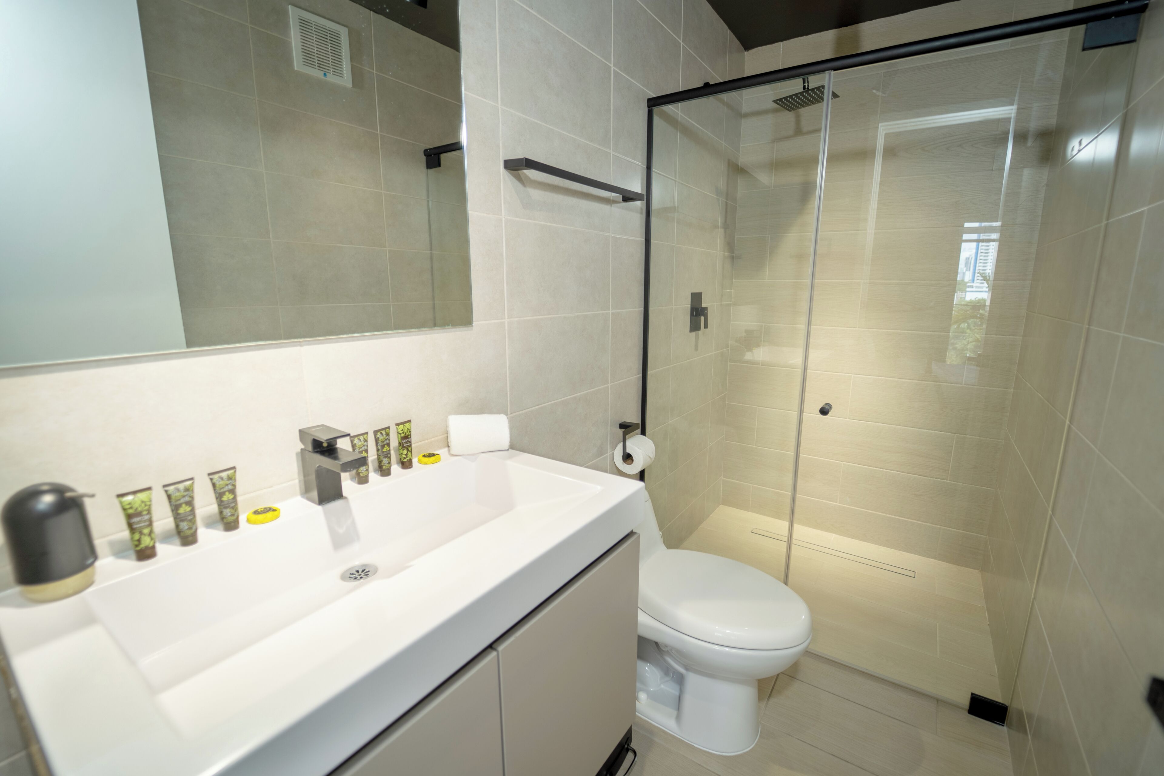 A modern bathroom with a white sink, toilet, and glass shower enclosure.