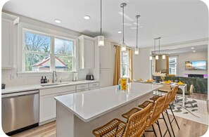 A modern kitchen with a central island, white cabinetry, and pendant lighting. - Brand New 3Bed3Bath•Downtown•Spacious•Patio•Modern (Raleigh)