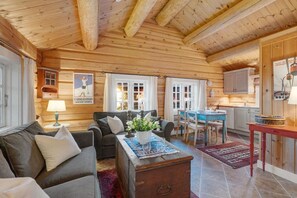En hyggelig interiør i en træhytte med stue, spiseområde og køkken.