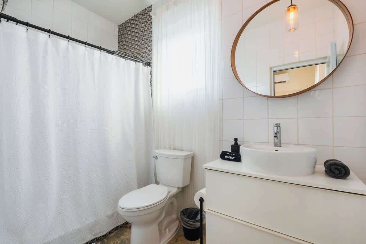 Un baño moderno con inodoro, lavamanos y espejo.