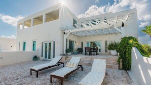 Un bâtiment moderne doté d’un patio aménagé avec des chaises longues et une pergola.