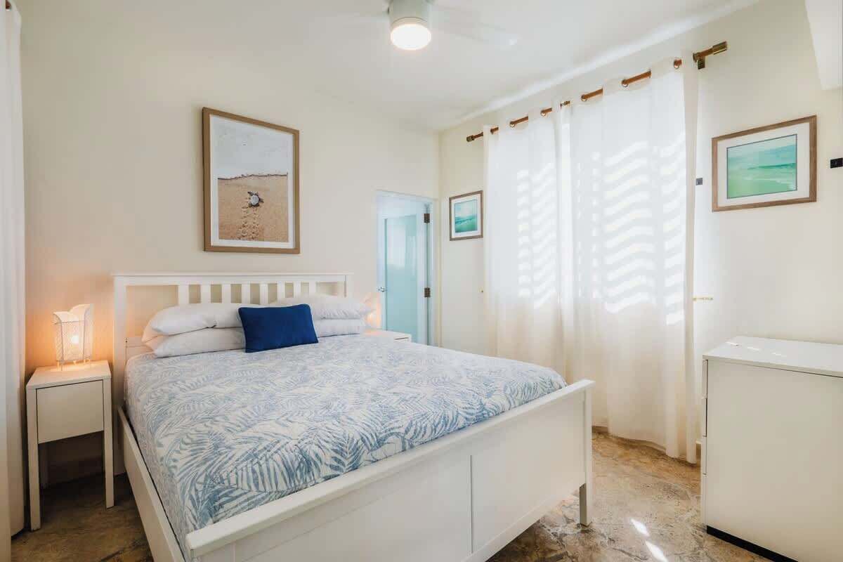 A bedroom with a bed, bedside table, and a small cabinet.