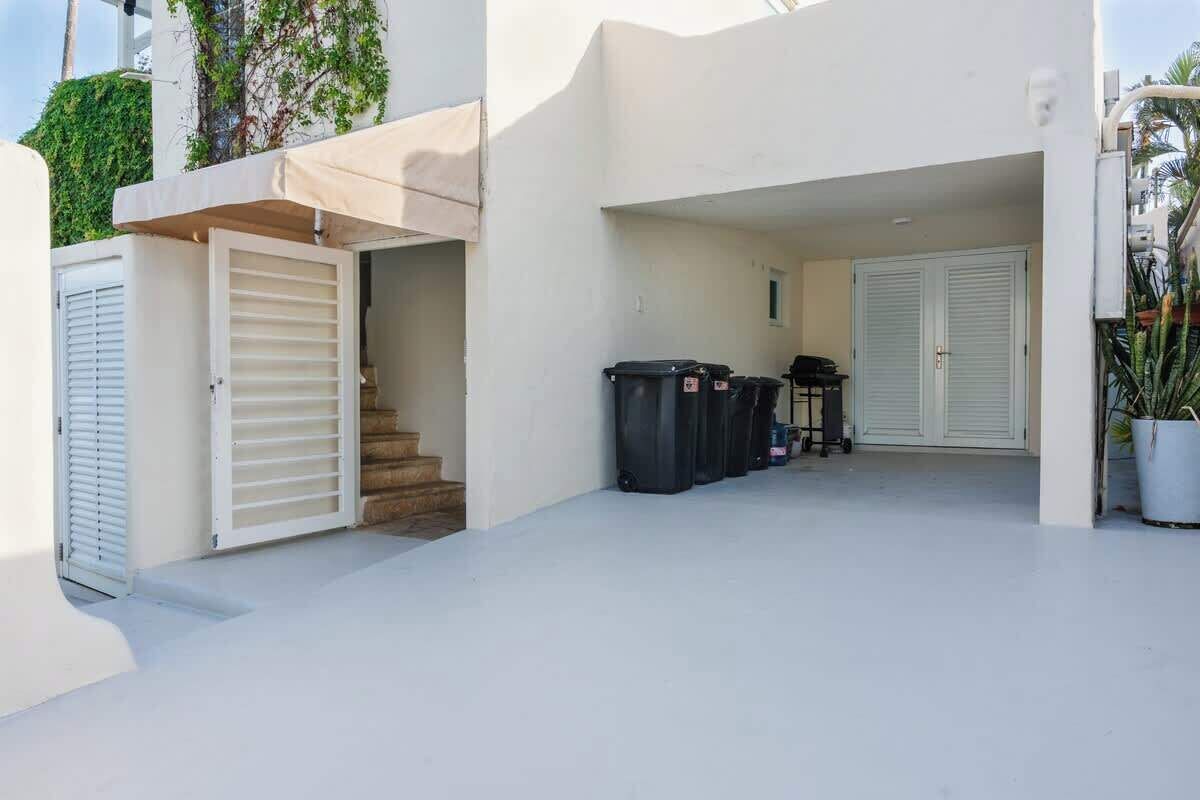 A clean, white exterior of a building with a covered entrance, a staircase, and a closed door.