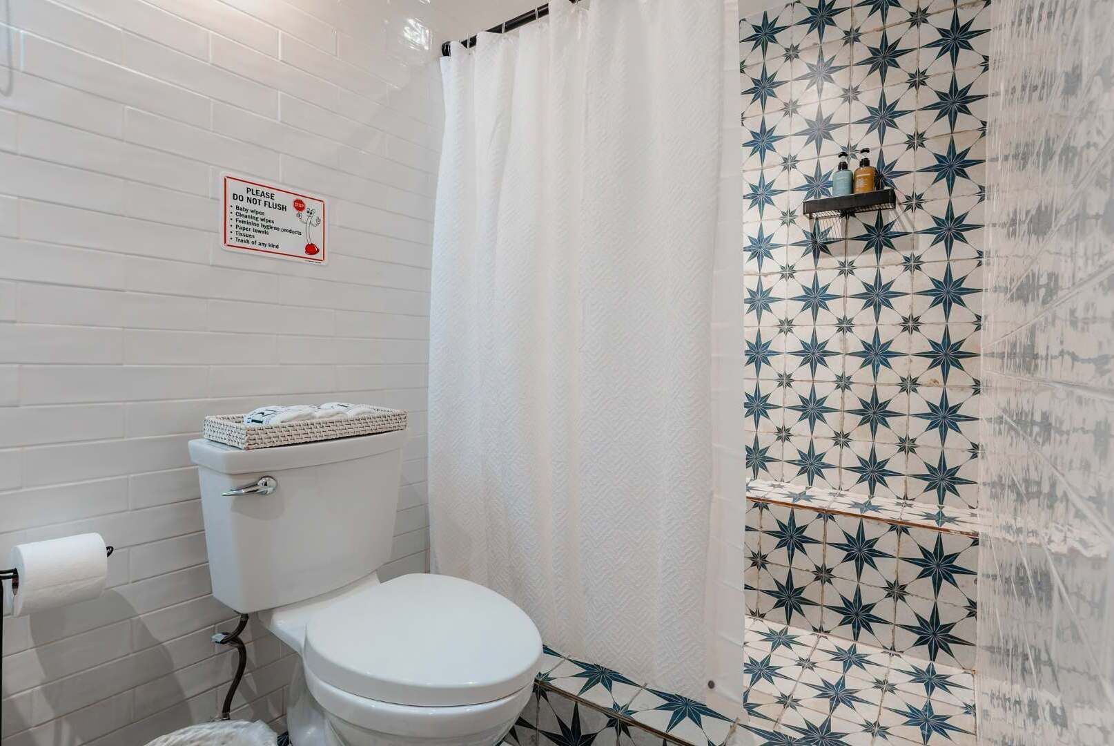 A bathroom with a white toilet, a shower curtain, and a wall with a star pattern.