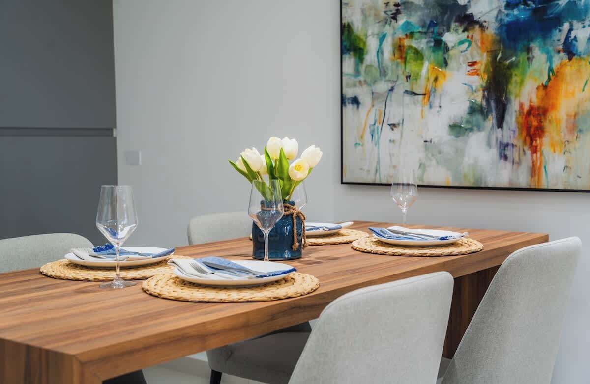 A dining table set with plates, cutlery, and glasses, with a vase of flowers in the center.