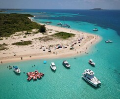 A beach with boats docked and people sunbathing.