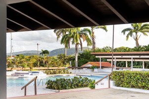 Zona de piscina con vistas a palmeras y montañas.