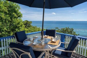 A round table with chairs and a table umbrella on a deck with a view of the ocean. - Le Sirenuse Paradise Haven in Culebra, Island (Culebra)