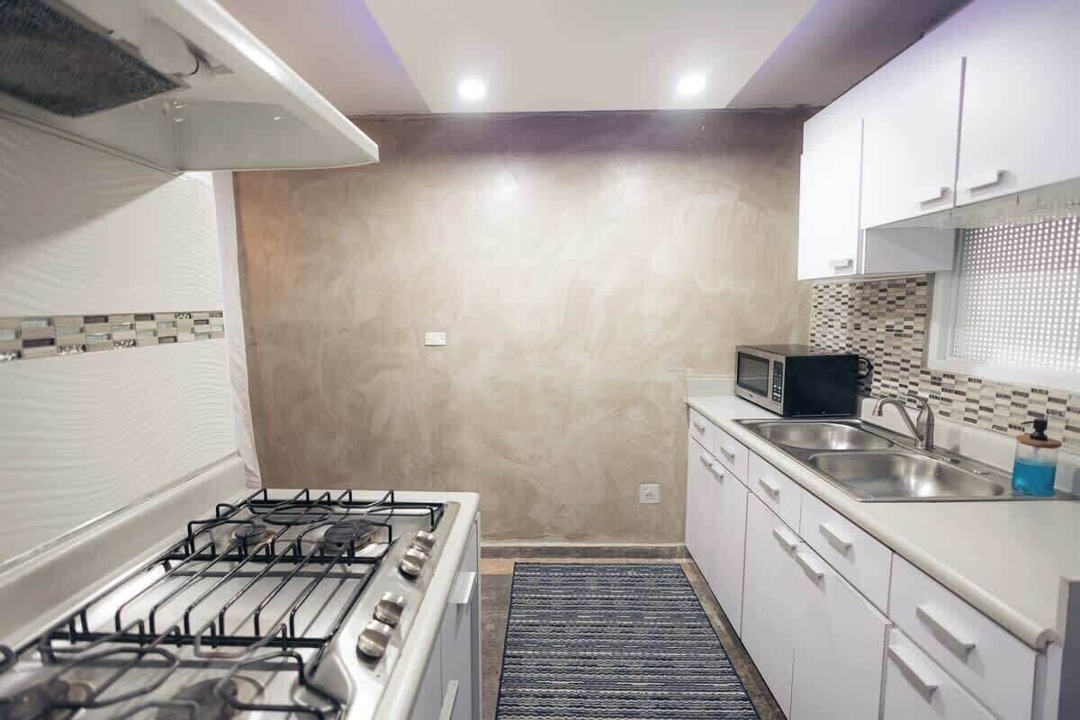 A compact kitchen with a gas stove, microwave, and white cabinets.