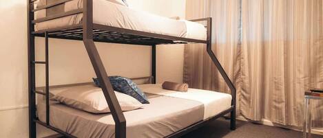 A bunk bed with a ladder, a small table, and a curtain.