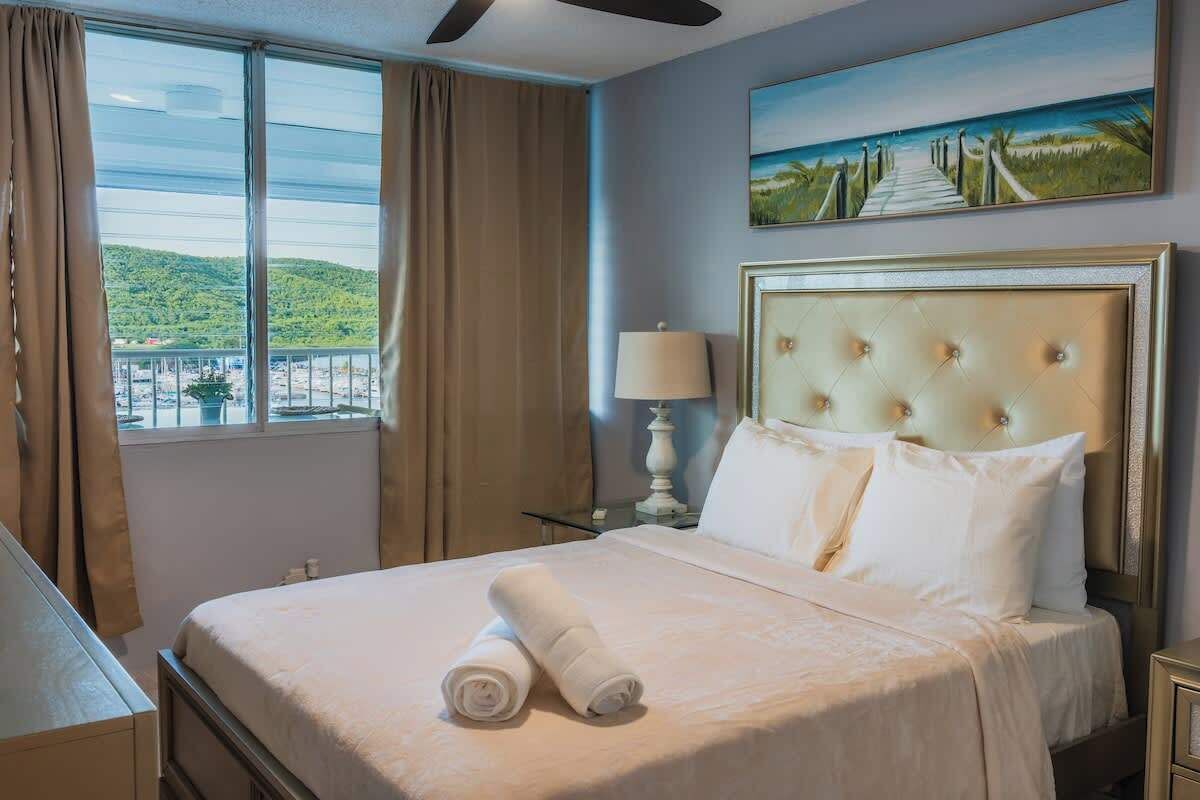 A hotel room with a large bed, a view of the sea, and a painting on the wall.