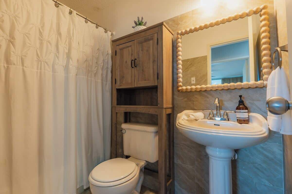 Un baño con inodoro, lavamanos y espejo.