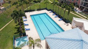 A swimming pool with blue water, surrounded by lounge chairs and palm trees, with buildings in the background. - Serenity Beach Vibe Stay in Costa Brava, Ceiba (Ceiba)
