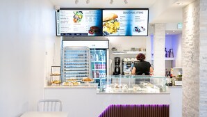 A cafe with a menu board, a counter with pastries, and a seating area with a bench. - Blü Zen, Ideal Couples Stay in Mameyes Rio Grande (Río Grande)