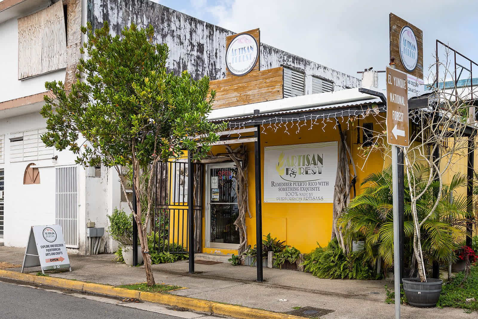 A storefront with a sign for 'ARTISAN FOREST' and a sign for 'EL Yunque National Forest'.
