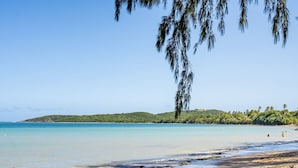 A beach with clear turquoise water, a sandy shore, and a distant green hill. - Blü Zen, Ideal Couples Stay in Mameyes Rio Grande (Río Grande)