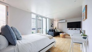 Ein modernes Schlafzimmer mit einem großen Bett, einer Couch, einem Esstisch und einem Fernseher.