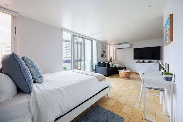 Une chambre moderne avec un grand lit, un canapé, une table à manger et un téléviseur.