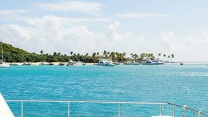 Ein Yachthafen mit Booten, die an einem sandigen Strand liegen, umgeben von Palmen und einem klaren Himmel.
