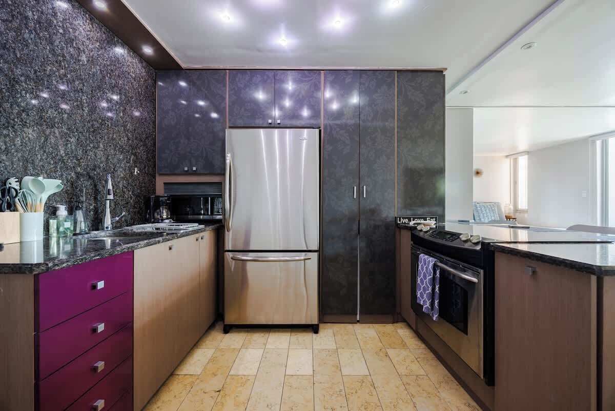 A modern kitchen with a stainless steel refrigerator, a built-in oven, and a granite countertop.