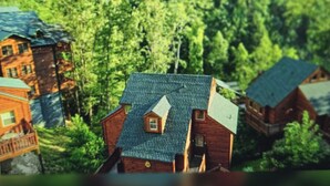Ein Modell einer Holzhütte mit geneigtem Dach, umgeben von dichtem, grünen Wald.