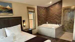Ein Hotelzimmer mit Bett, einem Badezimmer mit Badewanne und einer Holztür.