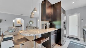 Uma cozinha moderna com ilha central, armários escuros e eletrodomésticos de aço inoxidável.