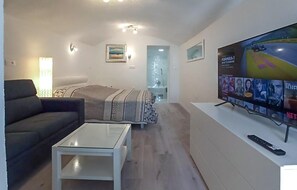 A modern living room with a sofa, a coffee table, a TV displaying movie posters, and a small table with a remote. - Nice home in Makarska with private swimming pool, can be inside or outside (Makarska)