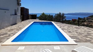 A rectangular swimming pool with a clear blue water, surrounded by a tiled deck. - Nice home in Makarska with private swimming pool, can be inside or outside (Makarska)
