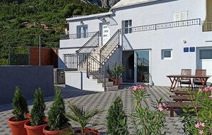 A modern two-story building with a staircase leading to a balcony, outdoor seating, and potted plants. - Nice home in Makarska with private swimming pool, can be inside or outside (Makarska)