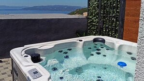 A hot tub with a control panel, surrounded by a wooden fence and a view of the sea. - Nice home in Makarska with private swimming pool, can be inside or outside (Makarska)