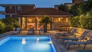 A swimming pool with lounge chairs and a patio area with a table and chairs. - Cozy home in Podstrana with private swimming pool, can be inside or outside (Podstrana)
