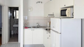 A compact kitchen with white cabinetry, a built-in microwave, a sink, and a kettle. - Amazing apartment in Podgora with house sea view (Podgora)