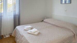 A neatly made bed with a quilted bedspread and two folded white towels on the foot of the bed. - Amazing apartment in Podgora with house sea view (Podgora)