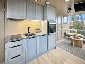 Een moderne keuken met grijze kastjes, een inbouwoven en een spoelbak.