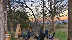 An outdoor seating area with chairs and a fire pit, surrounded by trees and a sunset view. - Private Pool & Pickleball Court | Pet-Friendly (Branson)
