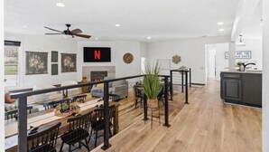 A spacious living area with a dining table, chairs, a fireplace, and a TV mounted on the wall. - Private Pool & Pickleball Court | Pet-Friendly (Branson)