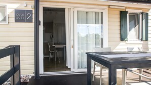 A modern, single-room accommodation with a sliding glass door entrance, a small kitchenette, and a dining area. - Gorgeous (sta)caravan in Drnis with WiFi (Drnis)