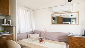 Una habitación pequeña con una mesa de madera, un banco acolchado y una kitchenette.