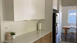 Une cuisine moderne avec des armoires blanches, un plan de travail en bois et un réfrigérateur noir.