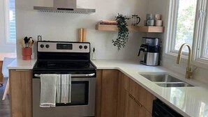 Une cuisine moderne dotée d’appareils électroménagers en acier inoxydable, de meubles en bois, d’un lave-vaisselle encastré et d’une fenêtre laissant entrer la lumière naturelle.