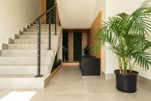 A modern staircase with a wooden finish and black railings, leading to a dark-toned landing area with a potted plant. - 3 King Bed Suite @CockleshellBeach w/View of Nevis (Southeast Peninsula)
