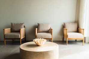 A room with three wooden armchairs with cushions, a round table with a decorative bowl, and a plain wall. - 2 King Bed Suite @CockleshellBeach w/View of Nevis (Southeast Peninsula)