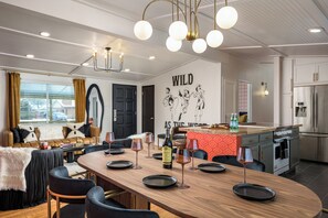 Een moderne eetruimte met een lange houten tafel, zwarte stoelen en een kroonluchter.